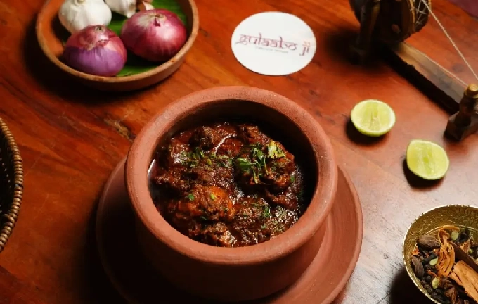A stylish wavy bowl of creamy butter chicken garnished with herb at Gulaabo Ji
