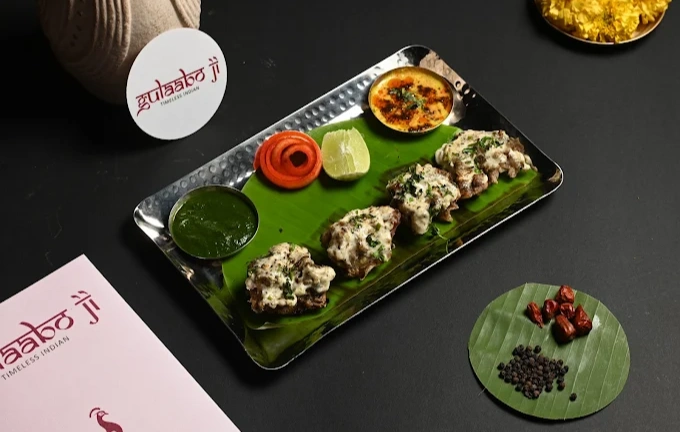 A stylish wavy bowl of creamy butter chicken garnished with herb at Gulaabo Ji